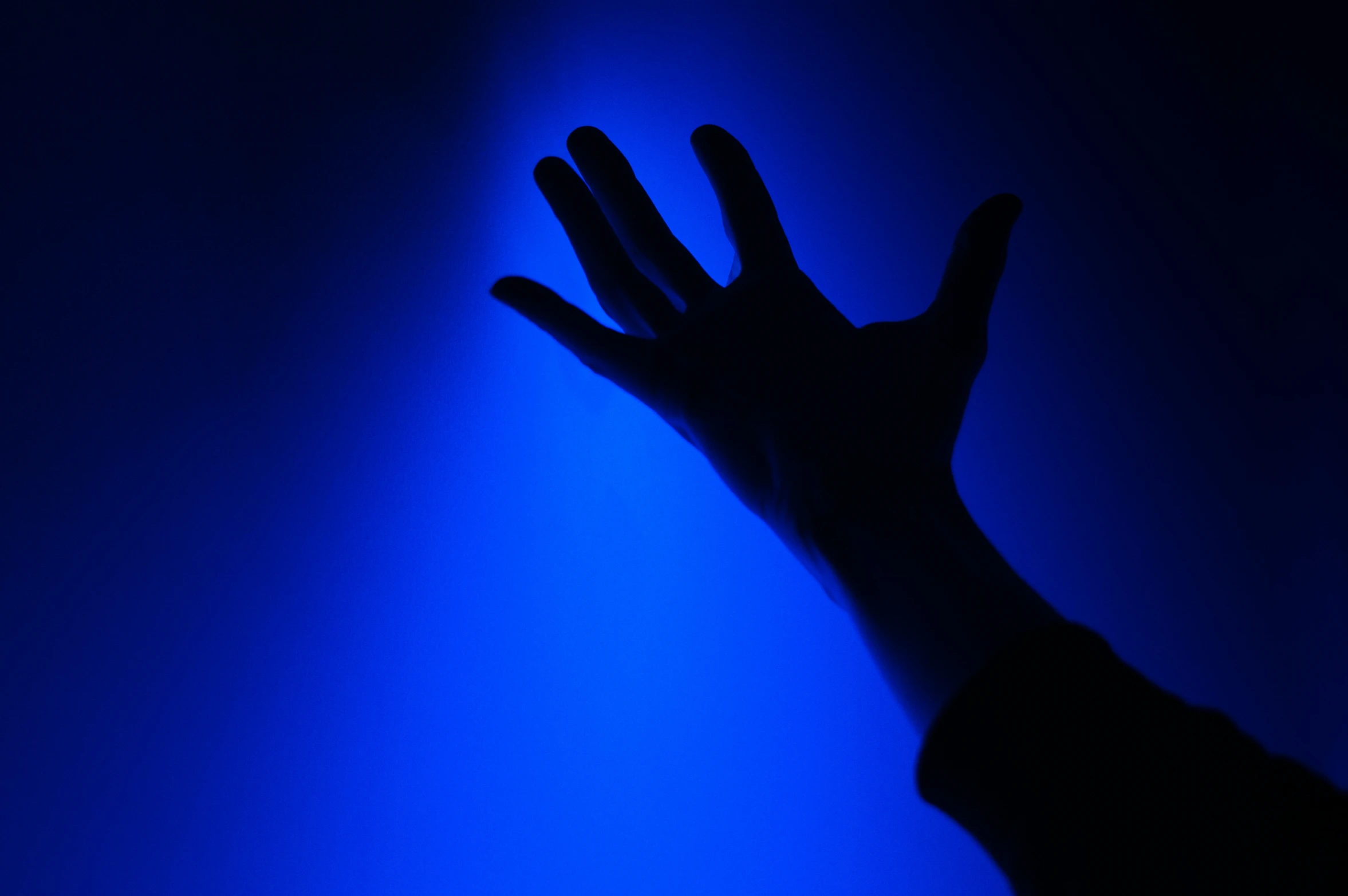 a hand reaching out towards a dark blue light