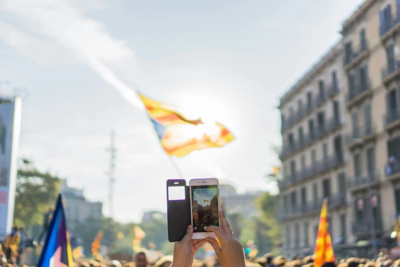 some people and buildings with a crowd and a phone