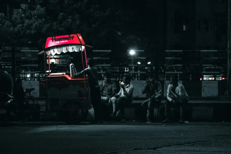 a red bus sitting in front of a building at night