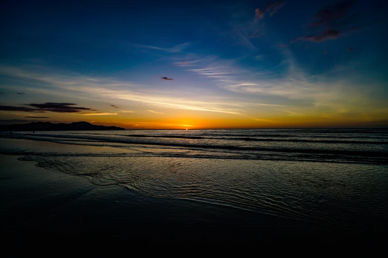 a sunset that is on the beach next to the water