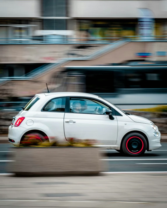 a small white car driving down a street