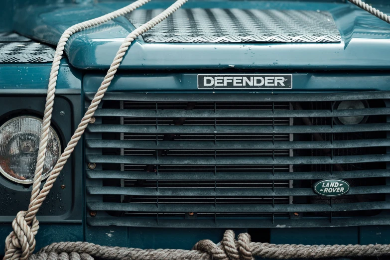 front of an old green truck with a rope tied around the front