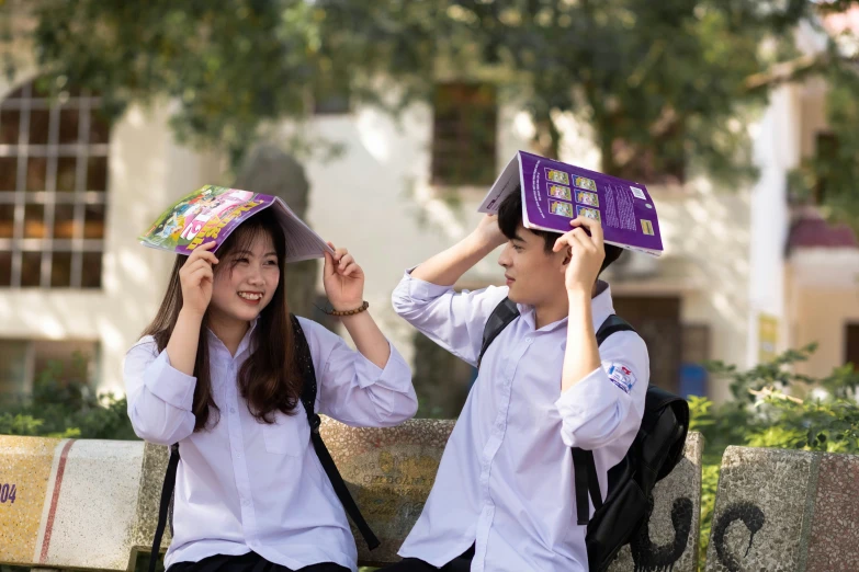 two young asian girls wearing hats sitting on a bench