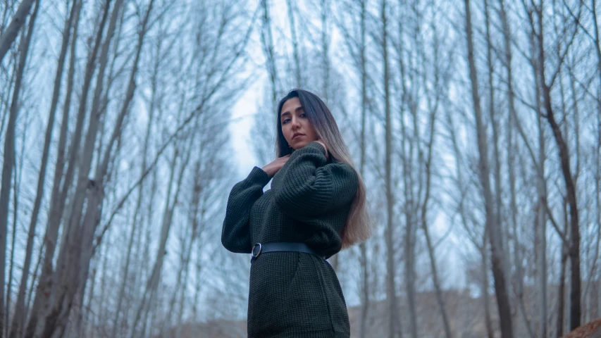 woman in coat outside in winter next to trees