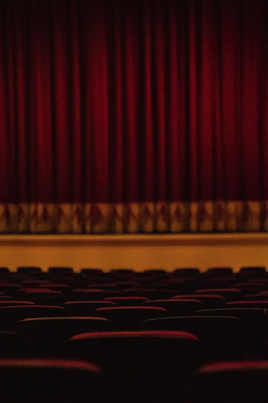 empty auditorium seats with red curtains and a microphone in front