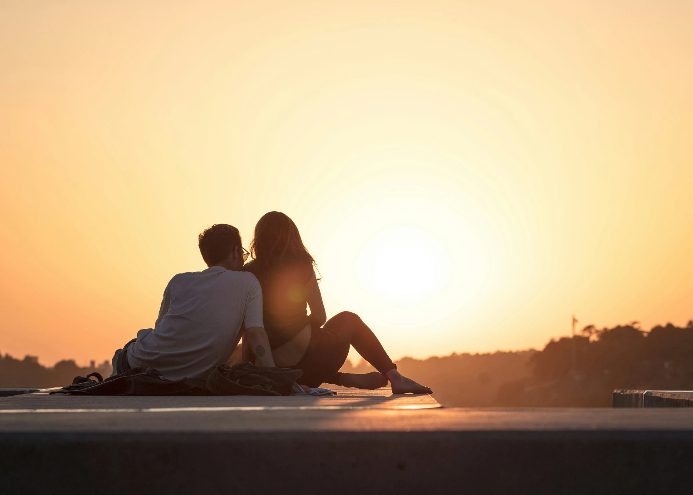 couple sitting on top of car as the sun sets