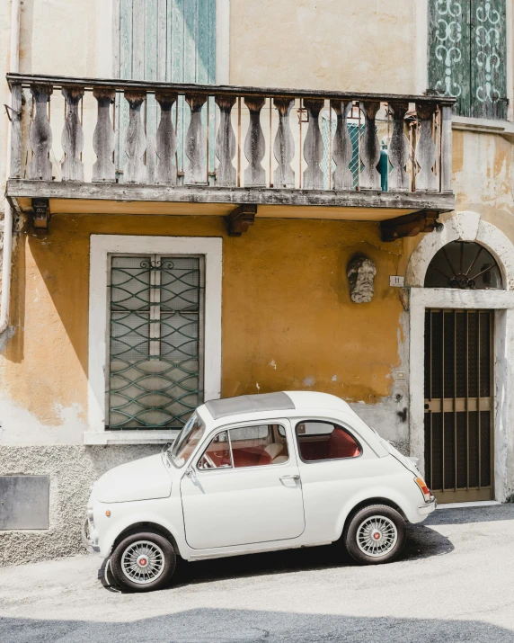 an old white car parked in front of an apartment building