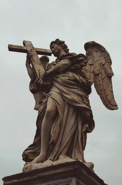 an angel carrying a cross on top of a monument