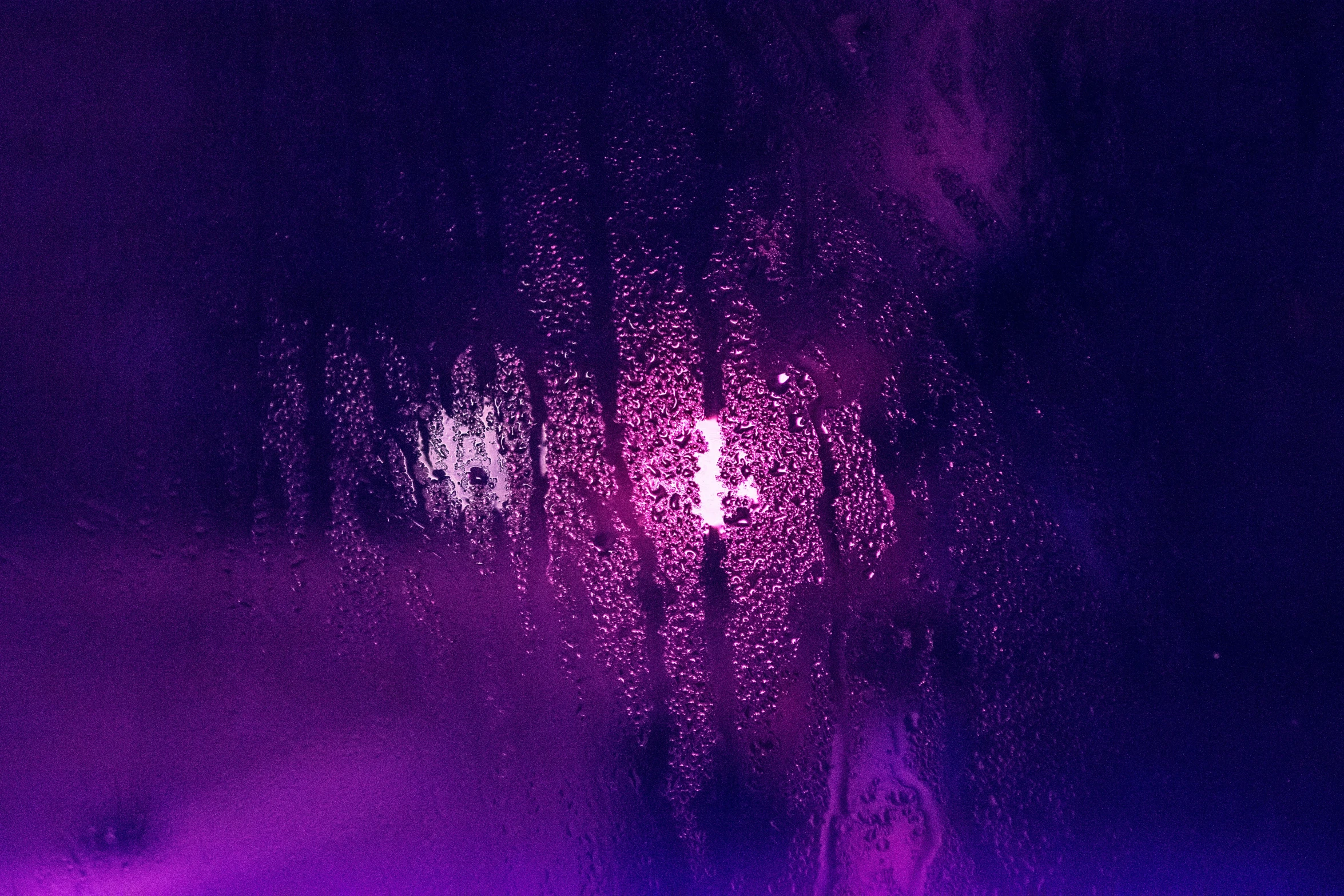 closeup of rain on a window glass with purple streaks