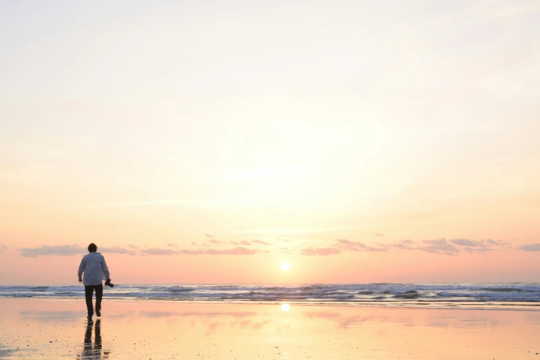 a person walking along a wet beach under a cloudy sky