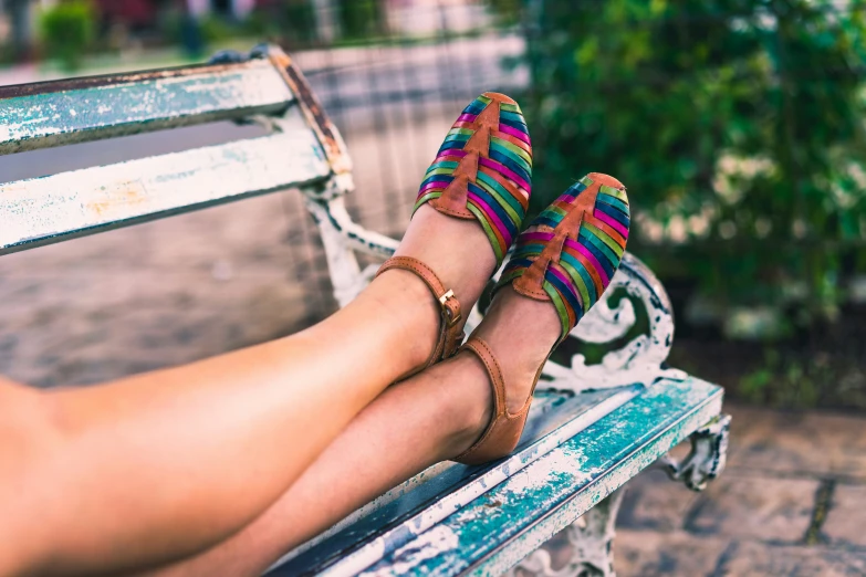 legs wearing colorful shoes on a park bench