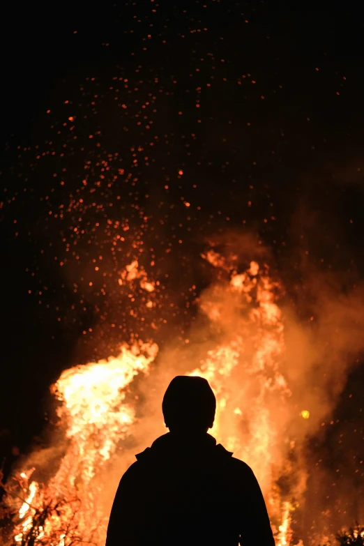 man in dark jacket silhouetted against bright orange fireball