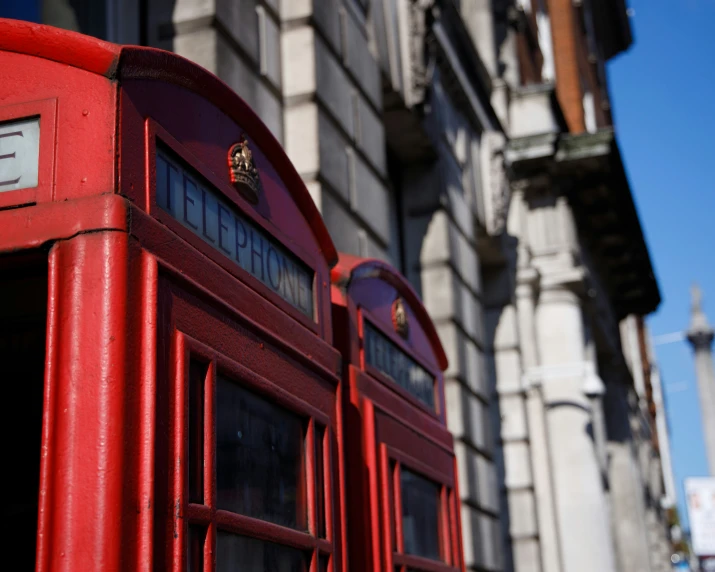 a red telephone booth in front of a tall building