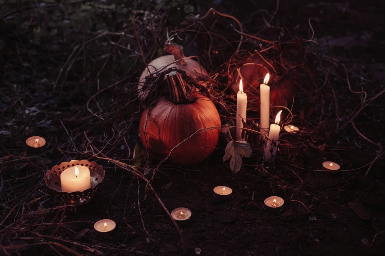 a candle lit arrangement with candles sitting near pumpkins