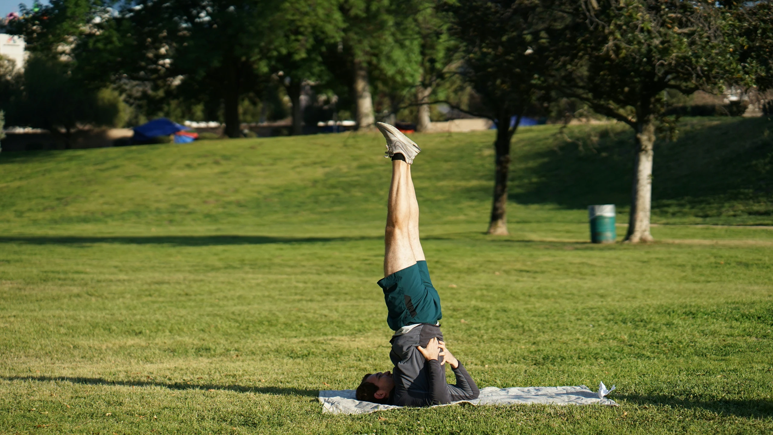 man on blanket doing handstand in grassy area