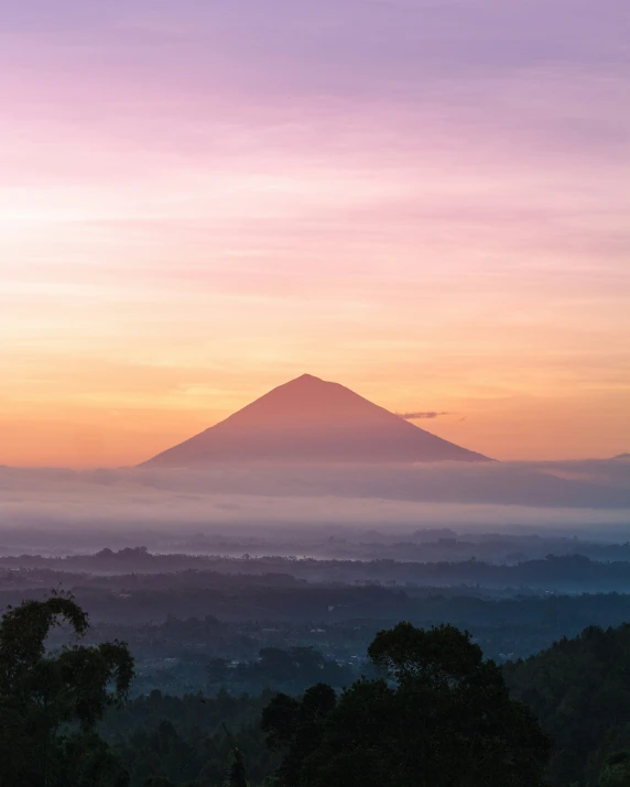 a mountain peak rises above a foggy valley