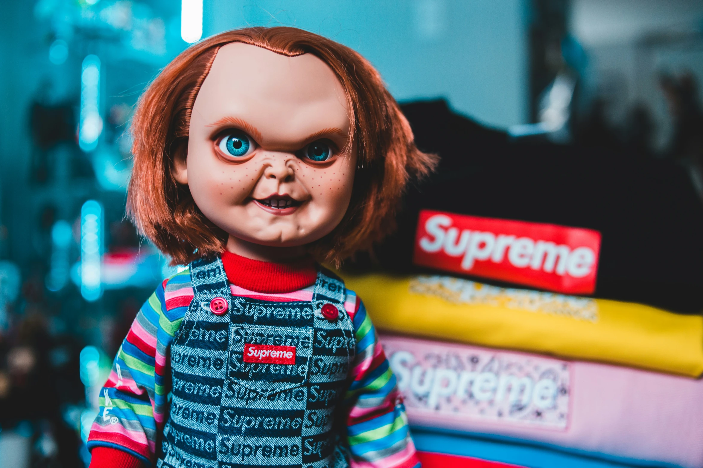 a creepy doll standing in front of a pile of shirts