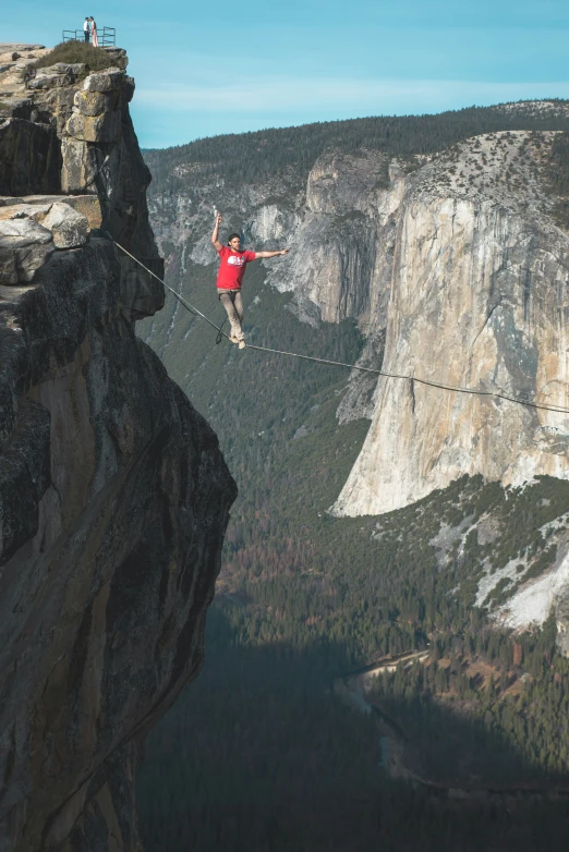 a person rapping on a rope high above a mountain range