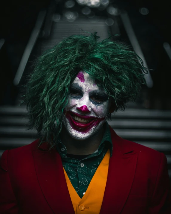 joker wearing green wig and red suit, standing by stairs