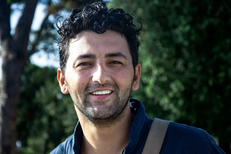 a smiling man with a blue shirt and suspenders on