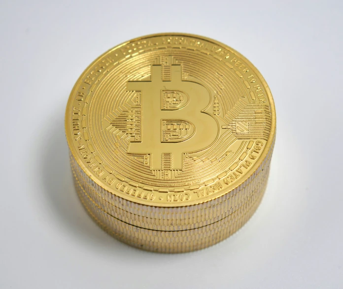 golden bitcoin sitting on top of a stack of five stacks