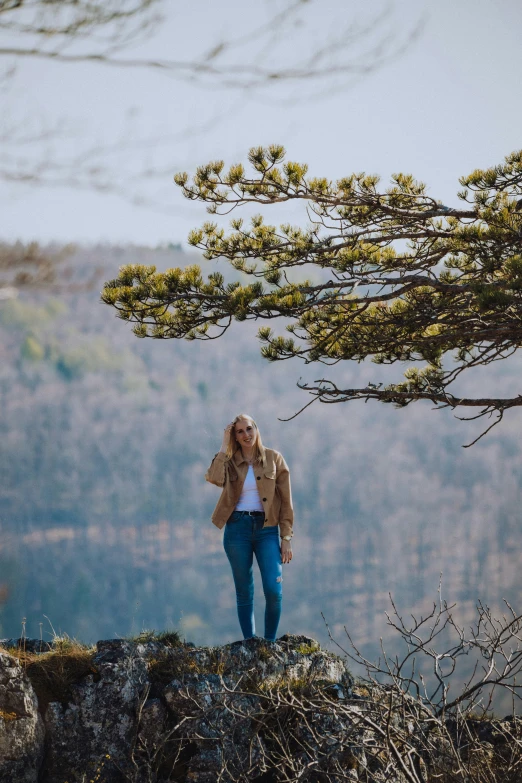 a person standing on a rocky hill near a tree