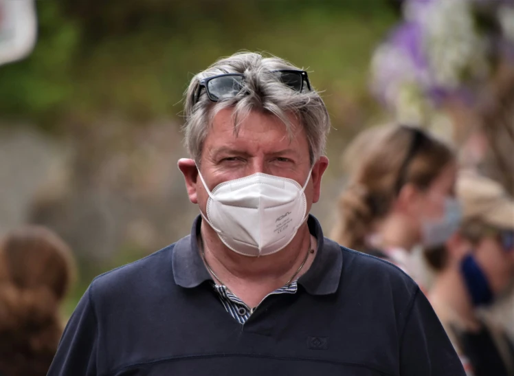 a man with sunglasses is wearing a face mask