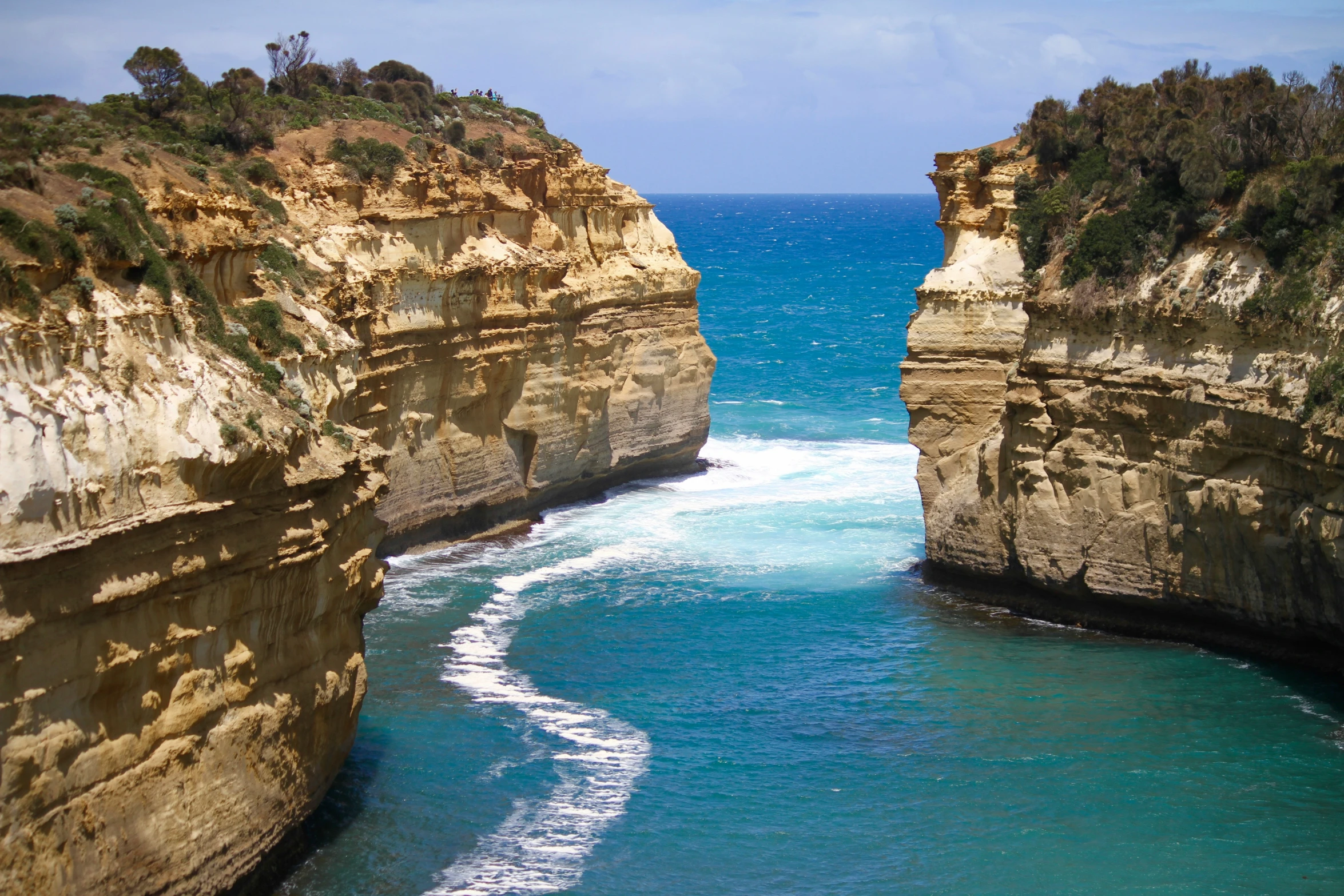 the coast is between two rock formations and blue water