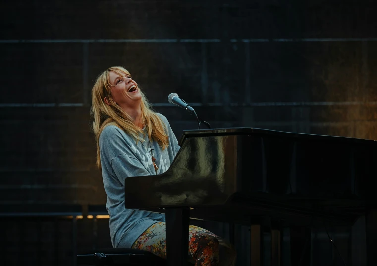 a woman singing on stage in front of a grand piano