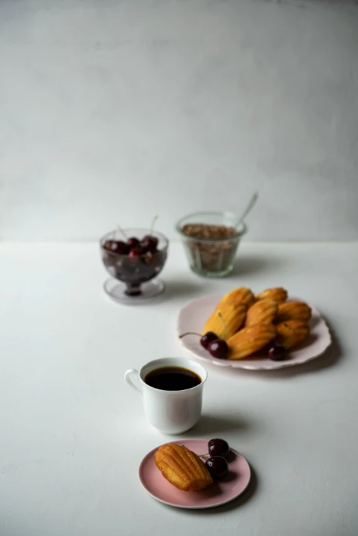 two plates of food, an almond creme sandwich, a cup of coffee and a bowl of berries