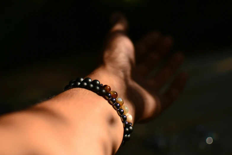 the hands of a man with different color beads on his wrist