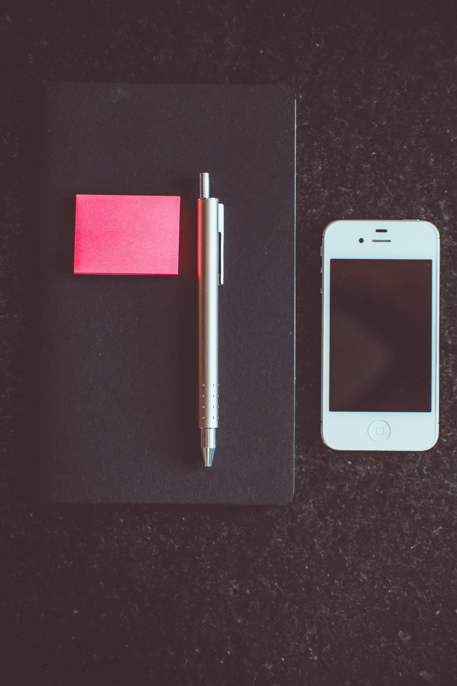 a cell phone and a pen sitting on a black table