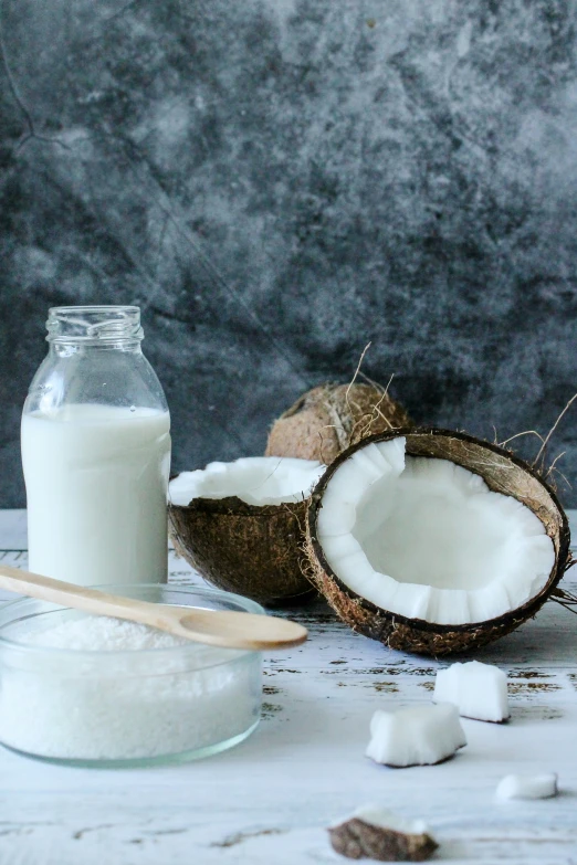 a glass bottle full of coconut and two whole coconuts