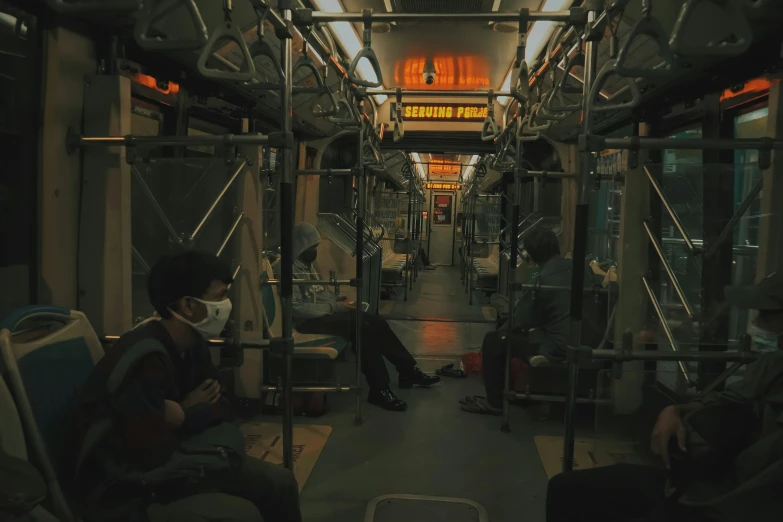 people wearing masks sitting on a train in a train station