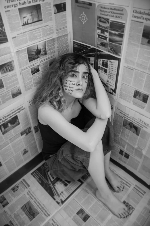 a woman covering her face while sitting in front of a newspaper