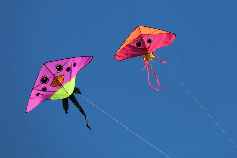 two kites are flying in the sky together