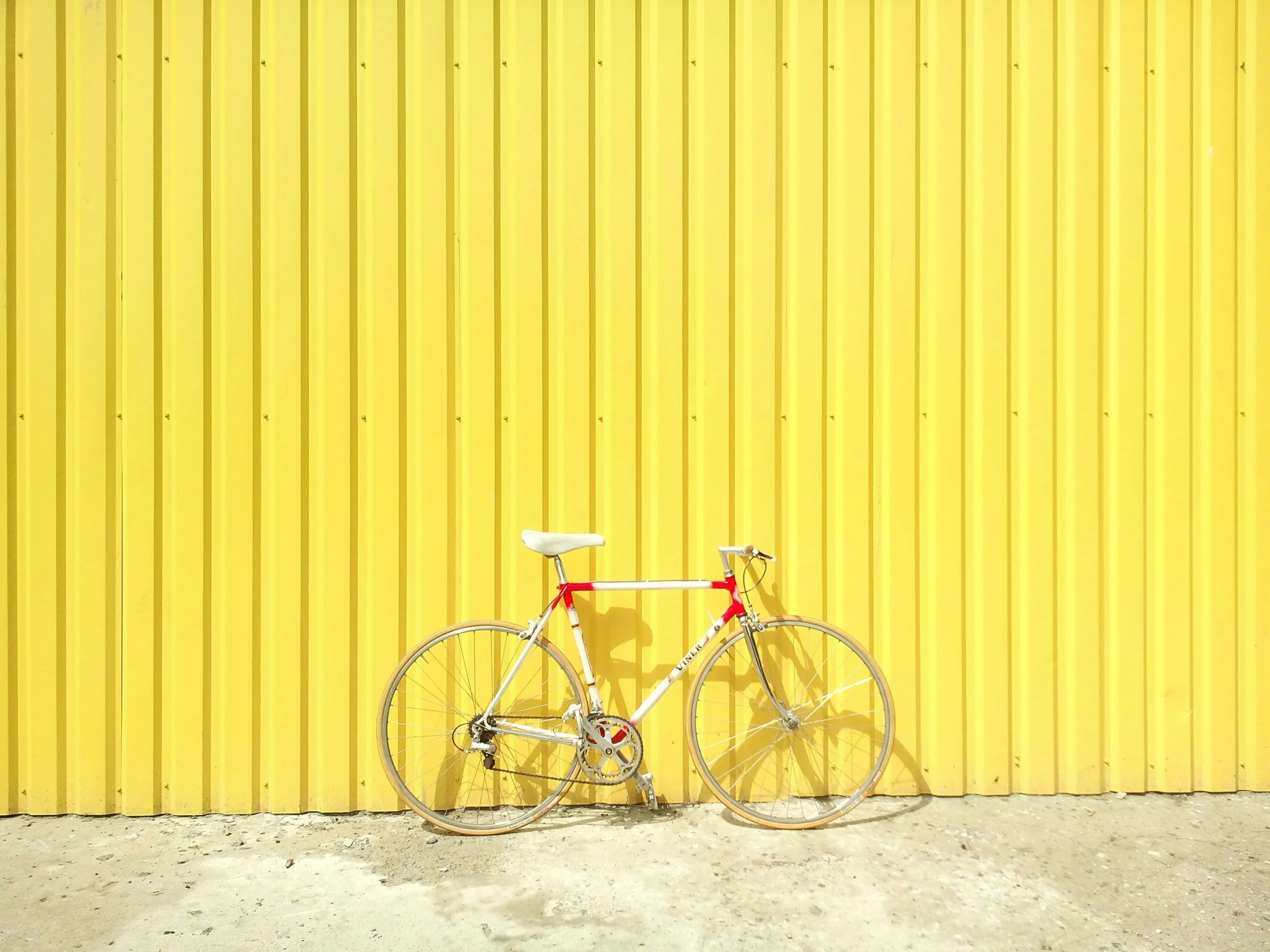 a bike leaning against a yellow wall with no wheel hubs