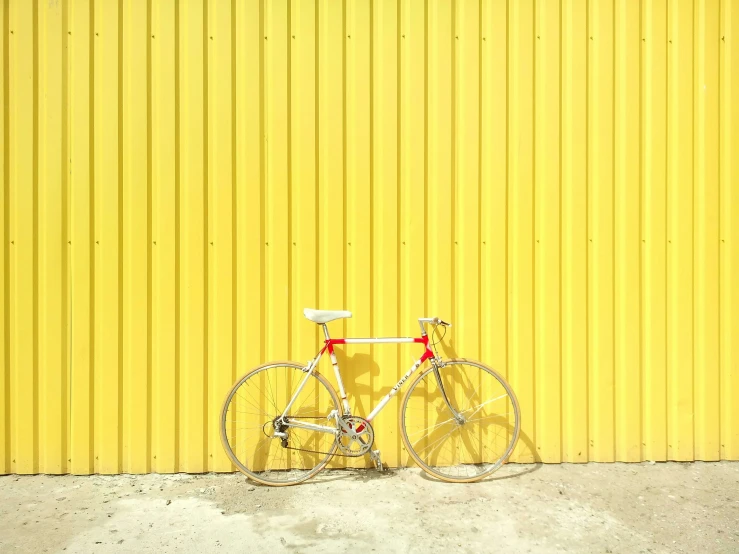 a bike leaning against a yellow wall with no wheel hubs