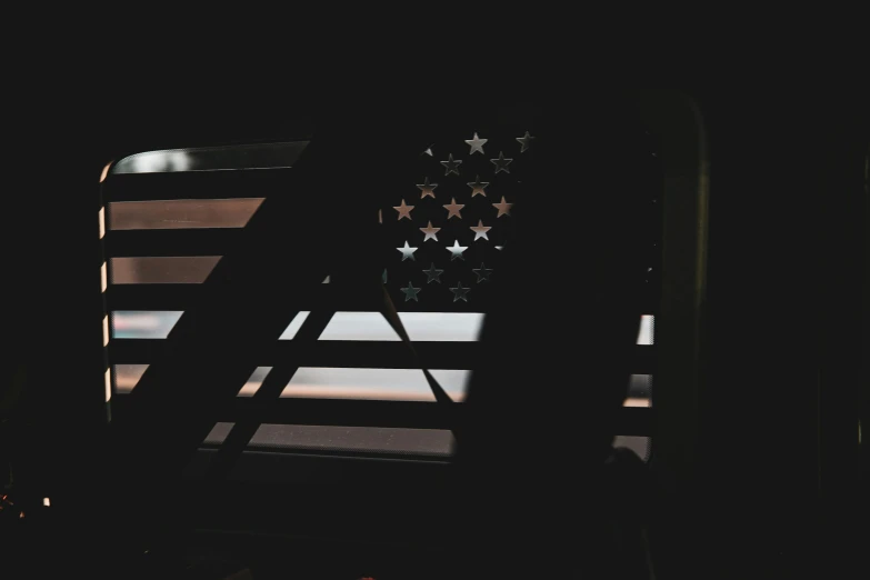 the american flag is displayed in silhouette on a window