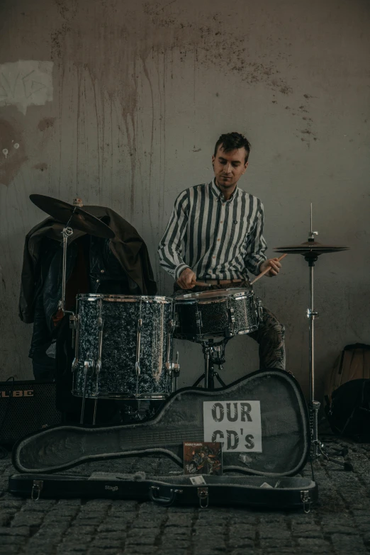 a man in striped shirt playing a drum set