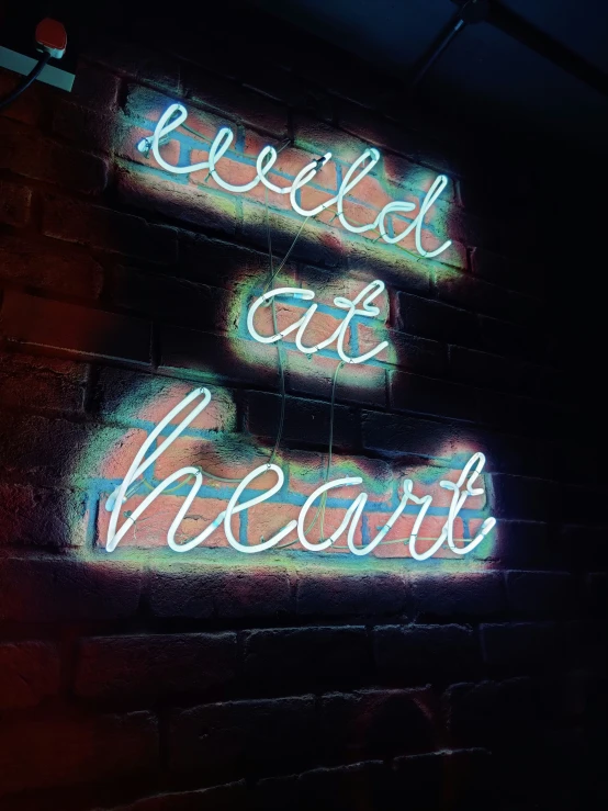 neon sign attached to brick wall with word'release cut hearts '