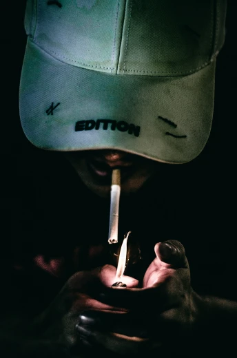 a person in a baseball cap lightening a cigarette