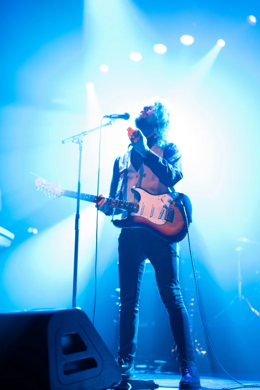 a man playing guitar in front of a microphone