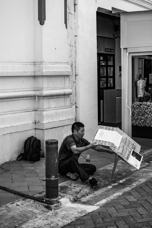 the man is holding a large box by the sidewalk