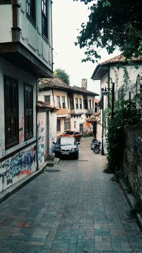 an old stone road surrounded by buildings with graffiti all over the walls