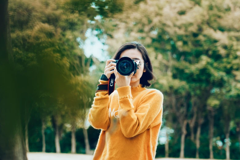 an asian woman holding up a camera