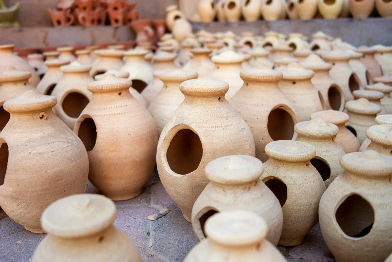 small, earthen colored ceramic vases are displayed in front of others