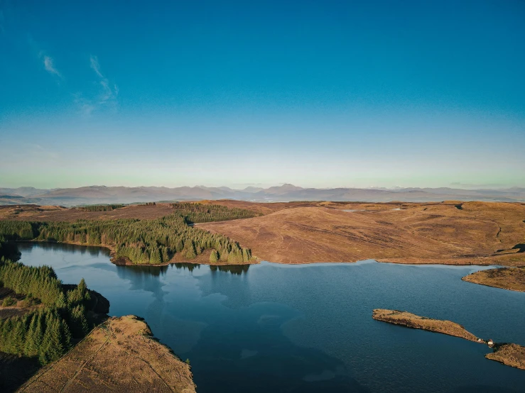 the lake is surrounded by mountains, and surrounded by dry grass