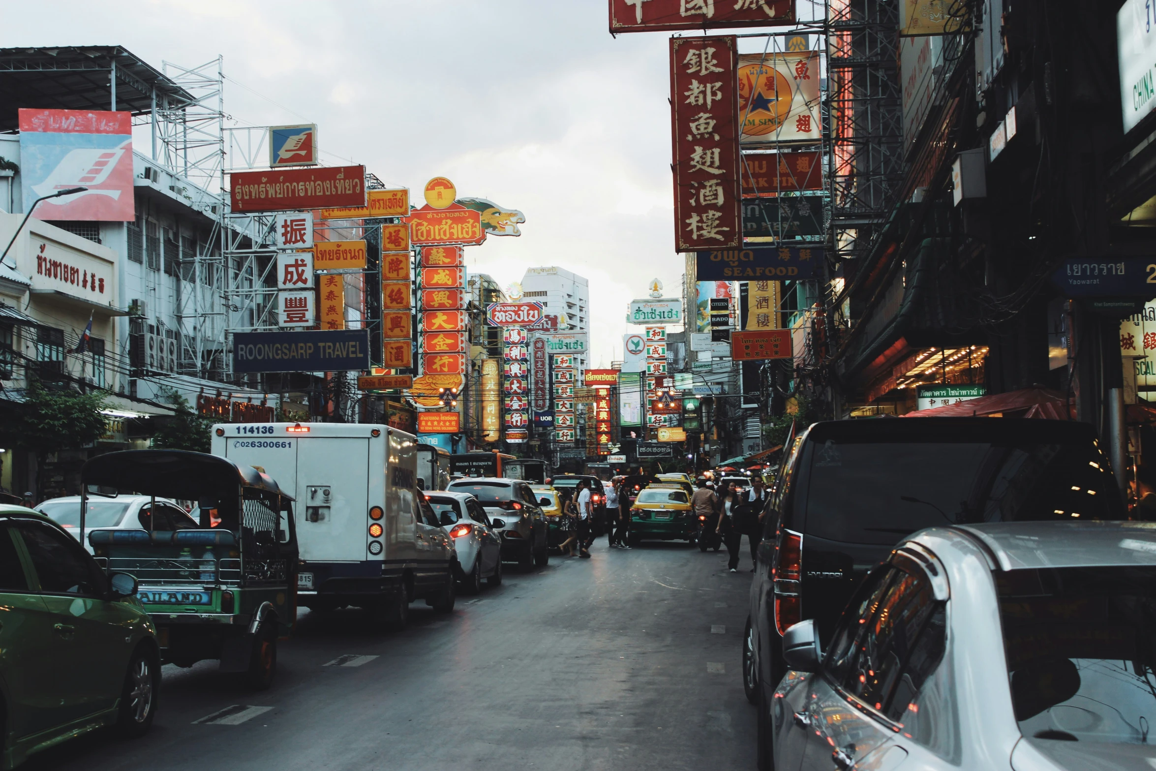 cars, signs and buses sit along a city street