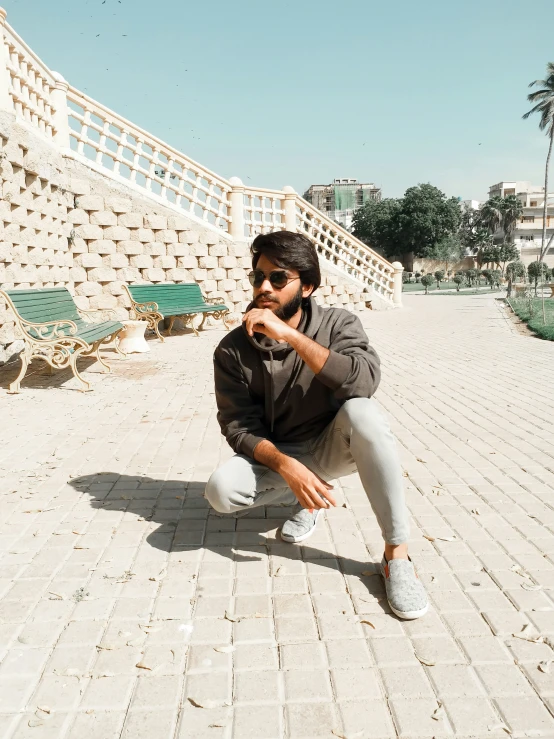 young man crouching on sidewalk holding soing in his hand